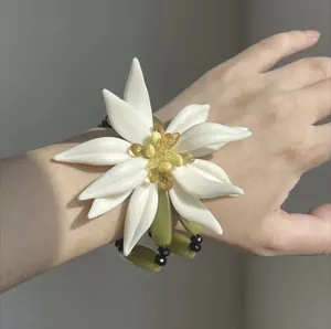 Primer plano de una gran pulsera de flores de resina blanca con centro amarillo en muñeca