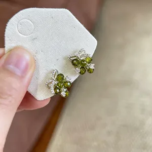 Primo piano di eleganti orecchini a lobo a fiore verde con accenti in zircone lucido.