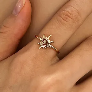 Close-up of a vintage rose gold sun spiral ring on a finger, showing intricate vortex details.