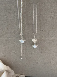 Primer plano detallado de collares con colgante de estrella plateada con perlas y piedras finas.