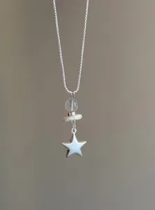Primer plano de un collar con colgante de estrella de plata minimalista con cuentas