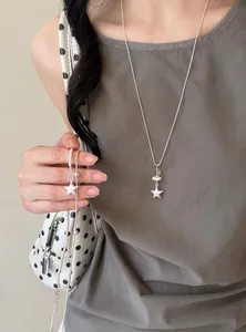 Primer plano de un collar minimalista de plata con colgante de estrella y perlas