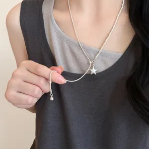Detalle macro de un elegante collar de perlas con colgante de estrella usado por una modelo
