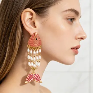 Close-up detail of exotic red fish enamel tassel earrings with white pearls and gold finish