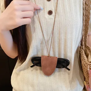 Detail der Brillenhalter-Halskette aus Leder, getragen mit Strickoberteil und Tasche
