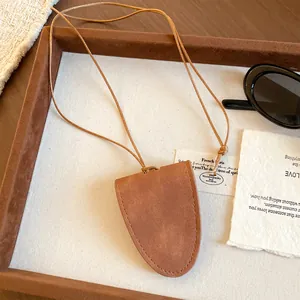 Nahaufnahme brauner Brillenhalter-Anhänger aus Wildleder mit Kordel auf Tablett