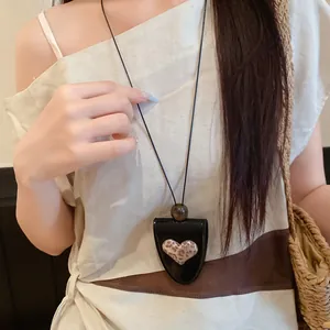 Detailansicht einer stilvollen Herzkette aus Leder an einem Model für Modestyling.