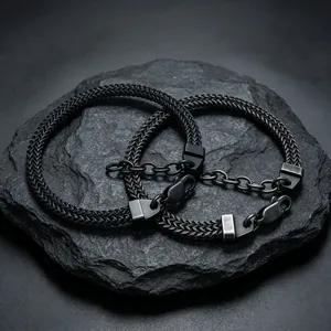Vue détaillée de deux bracelets en acier inoxydable noir sur un rocher texturé.