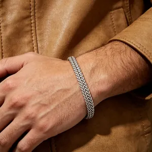 Détail d'un bracelet chaîne en acier inoxydable argenté porté au poignet d'un homme.