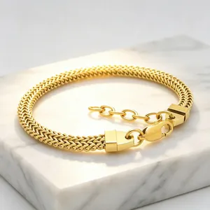 Vue détaillée d'un bracelet gourmette en acier inoxydable doré sur un support en marbre