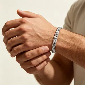 Gros plan d'un bracelet gourmette en acier inoxydable argenté sur un poignet masculin.