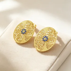 Nahaufnahme französischer Vintage-Ohrstecker mit Filigranmuster und blauer Blume.