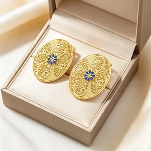 Detailansicht von goldenen Vintage-Ohrringen mit blauem Emaille und Filigranmuster.