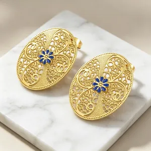 Nahaufnahme goldener filigraner Vintage-Ohrstecker mit blauer Emaille-Blume im Barockstil.
