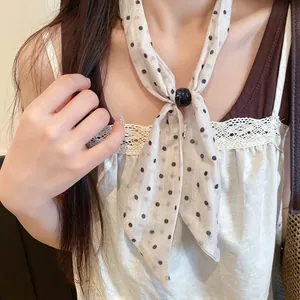 Detalle de un pañuelo francés de lunares anudado con una cuenta negra en una modelo.