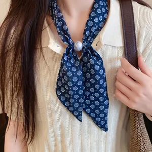 Detalle de bufanda estrecha de flores azul marino con anillo efecto mármol en top crema