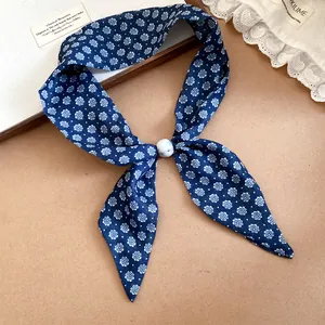 Detalle de una bufanda de seda con flores azules y una cuenta deslizante de efecto mármol