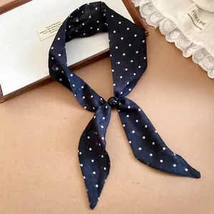 Detalle de una bufanda fina de lunares azul marino estilo francés con hebilla negra chic.