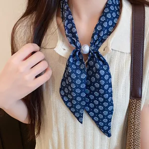 Primer plano de bufanda fina de seda con flores azules y elegante anillo de mármol