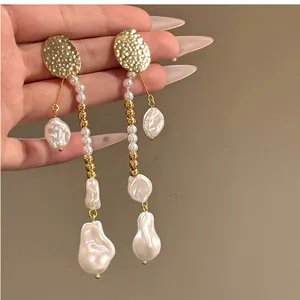 Détail de boucles d'oreilles pendantes en perles baroques vintage avec clous dorés