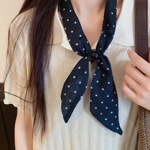 Detalle de una bufanda estrecha negra con lunares blancos de estilo francés para el cuello