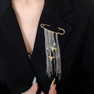 Detailed macro view of golden bird pendant and silver tassel chain brooch on a suit