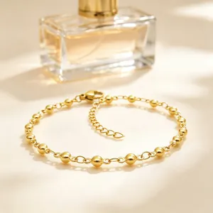 Dettaglio di un bracciale in acciaio inossidabile dorato con maglie a sfere regolabili.