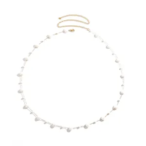 Elegant gold stainless steel body chain with white shell beads on white background