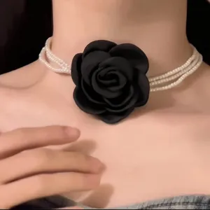 Nahaufnahme eines mehrsträngigen Perlen-Chokers mit einer großen schwarzen Stoffblume.