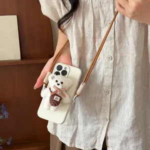 Detailed view of the plush teddy bear pendant and nylon crossbody strap on a phone case