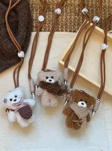 Detailed view of plush bear pendants with knitted scarves and adjustable nylon straps