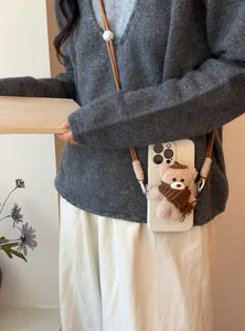 Detail view of a cute plush bear phone strap with a brown nylon crossbody cord.