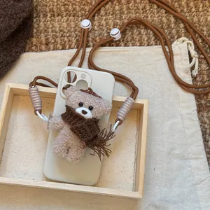 Close-up view of a cute plush bear pendant with a double-layered brown nylon crossbody strap