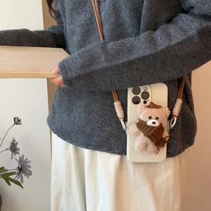 Detail of a cute plush bear charm wearing a scarf on a double nylon phone strap cord