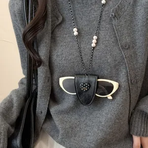 Stylische Brillenclip-Halskette aus schwarzem Leder mit Herz über grauem Cardigan
