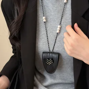Gros plan d'un élégant pendentif de collier en cuir avec un ornement de chat à pois.