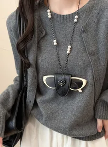 Nahaufnahme einer Brillenclip-Halskette aus Leder mit Perlen und beige Sonnenbrille