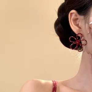 Nahaufnahme eines rot gepunkteten Blumenohrrings mit Metalllackierung am Ohr eines Models