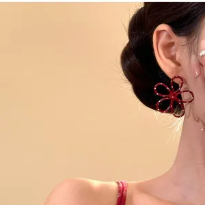 Makro-Detailansicht der roten hohlen Blumenohrstecker mit Punkten am Ohr des Models