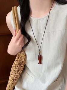 Dettaglio di una collana con pendente a forma di pesce in legno in stile cinese vintage.