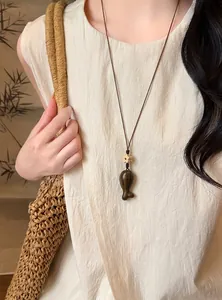 Dettaglio di una collana con ciondolo a forma di pesce in legno fatto a mano