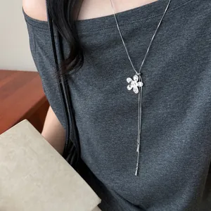 Détail d'un collier avec pendentif fleur argenté porté sur un t-shirt gris sobre