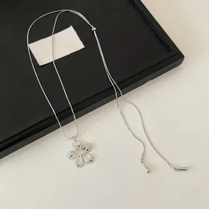 Gros plan d'un collier pendentif fleur en argent minimaliste avec texture martelée