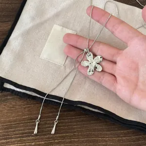 Gros plan d'un collier pendentif fleur argenté brillant avec chaîne ajustable