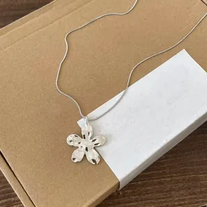 Gros plan d'un collier pendentif fleur argenté doté d'une élégante finition texturée.