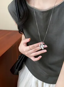 Détail d'un collier avec pendentif fleur en argent porté par un mannequin en vert