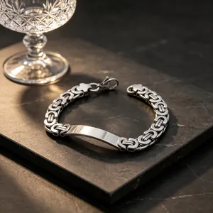 Close-up of a silver Byzantine chain bracelet with a polished ID plate on black stone