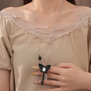 Detailed view of a black butterfly key necklace with rhinestones and a glass teardrop