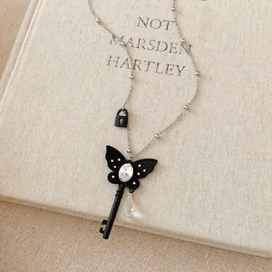 Detailed close-up of a black butterfly key necklace with crystal drops on a linen book