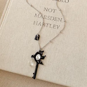 Close-up of a black swallow key pendant necklace with rhinestone on a vintage book